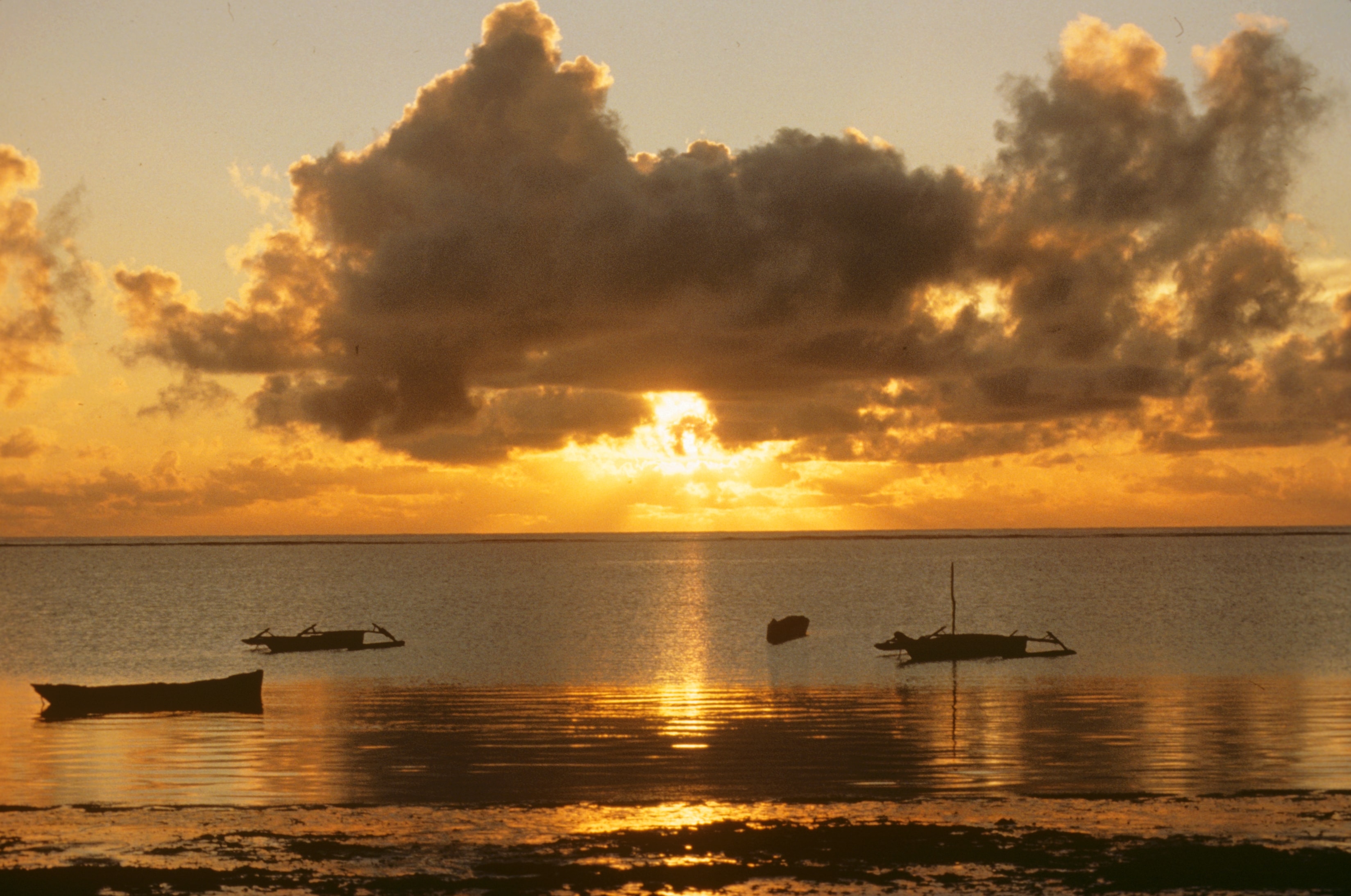 Fishing boats silhouetted on calm water at sunset in Africa