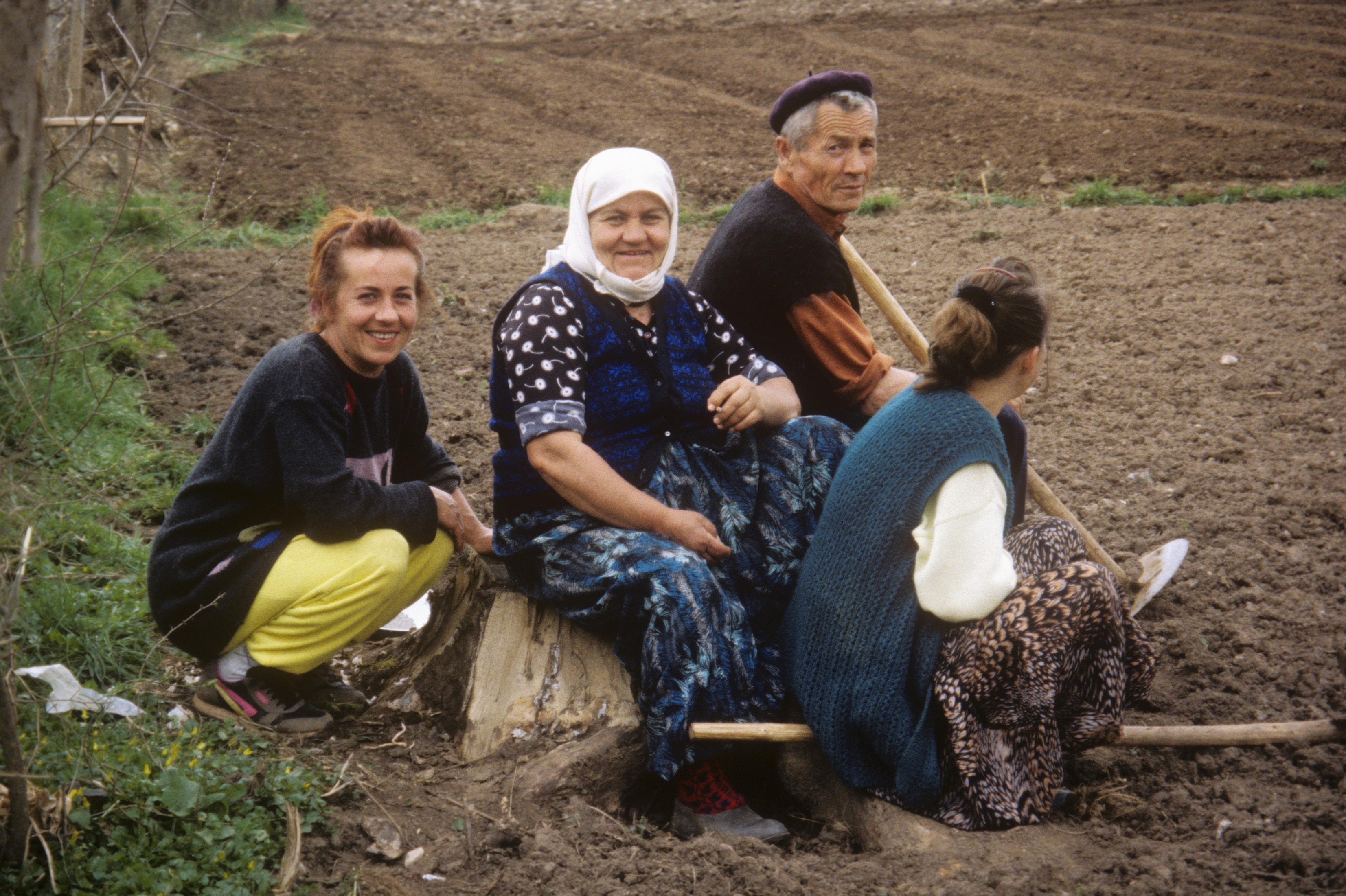 Family resting together in a freshly plowed farm field in Bosnia