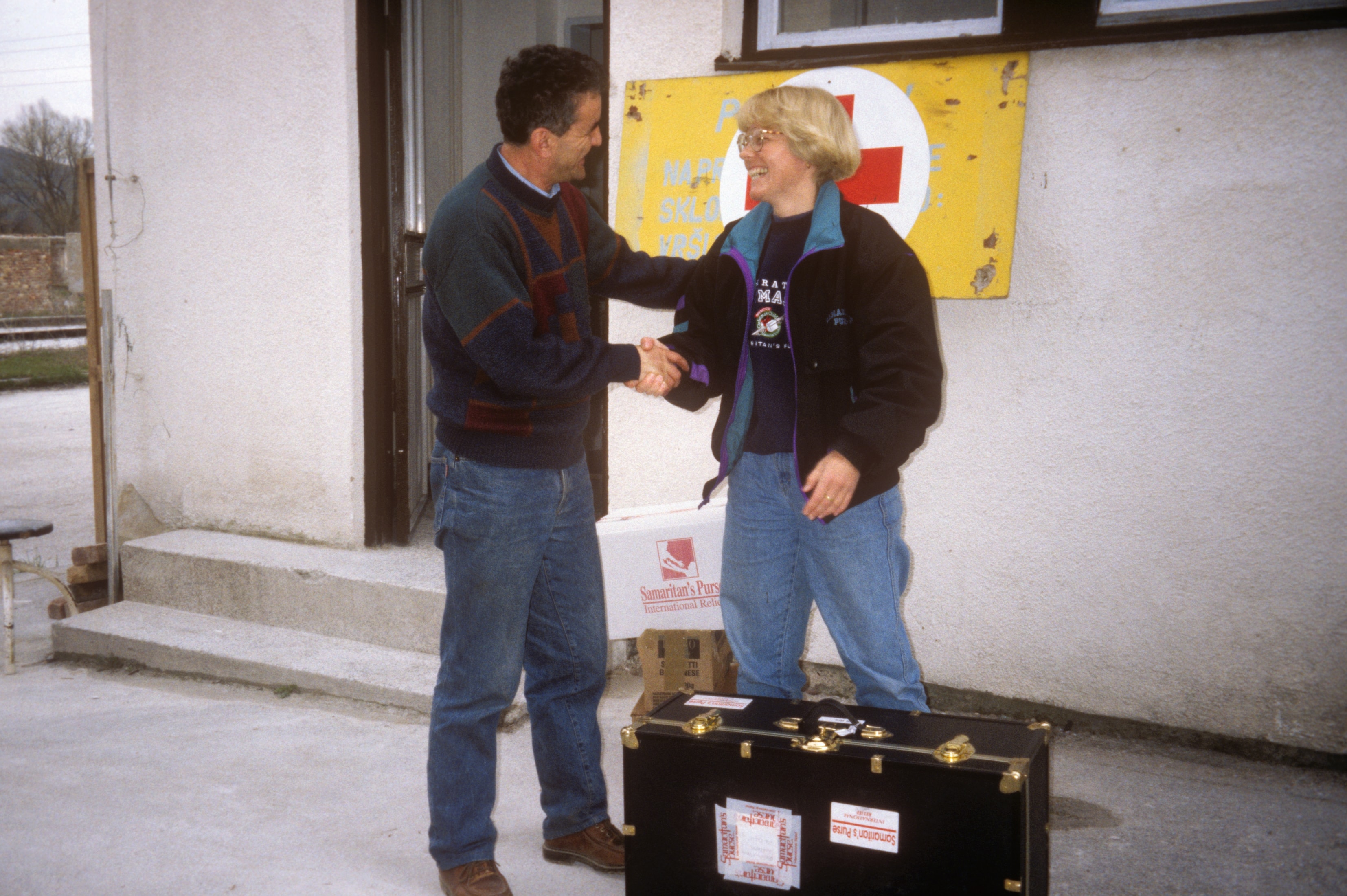 Dr. Susan Vitalis shaking hands outside a Red Cross building in Bosnia