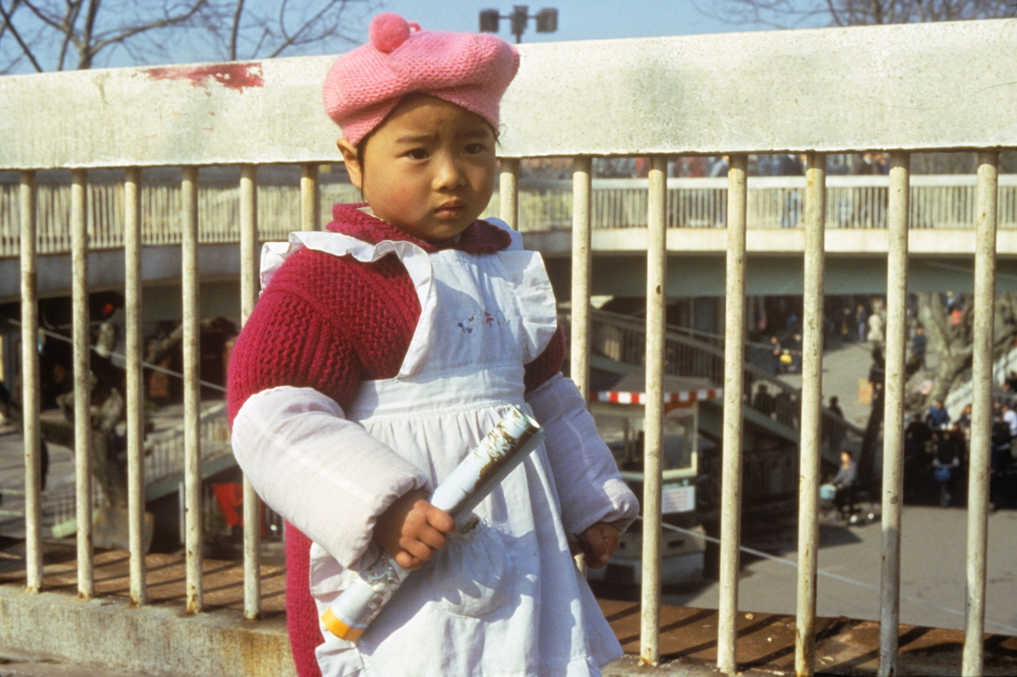 Girl in pink beret standing at railing, China