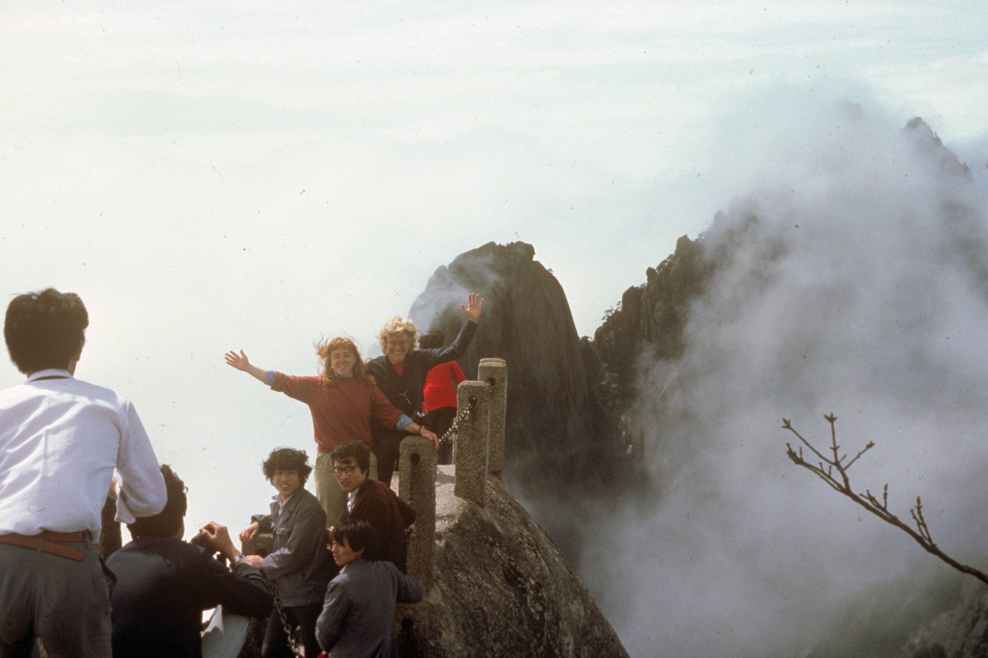 Group waving on misty mountain peak, China