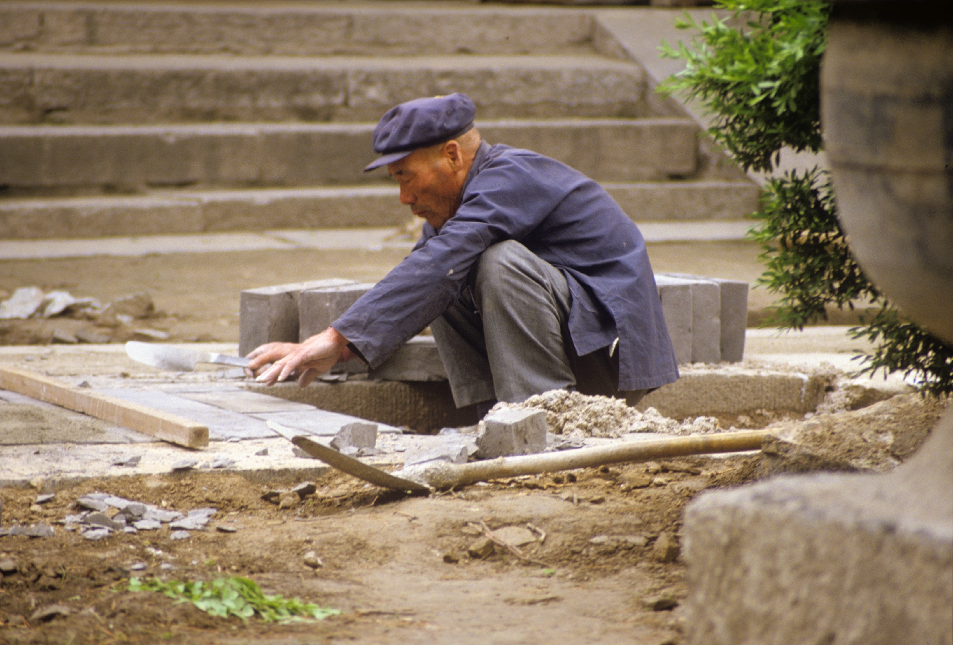 Stonemason laying bricks outdoors, China