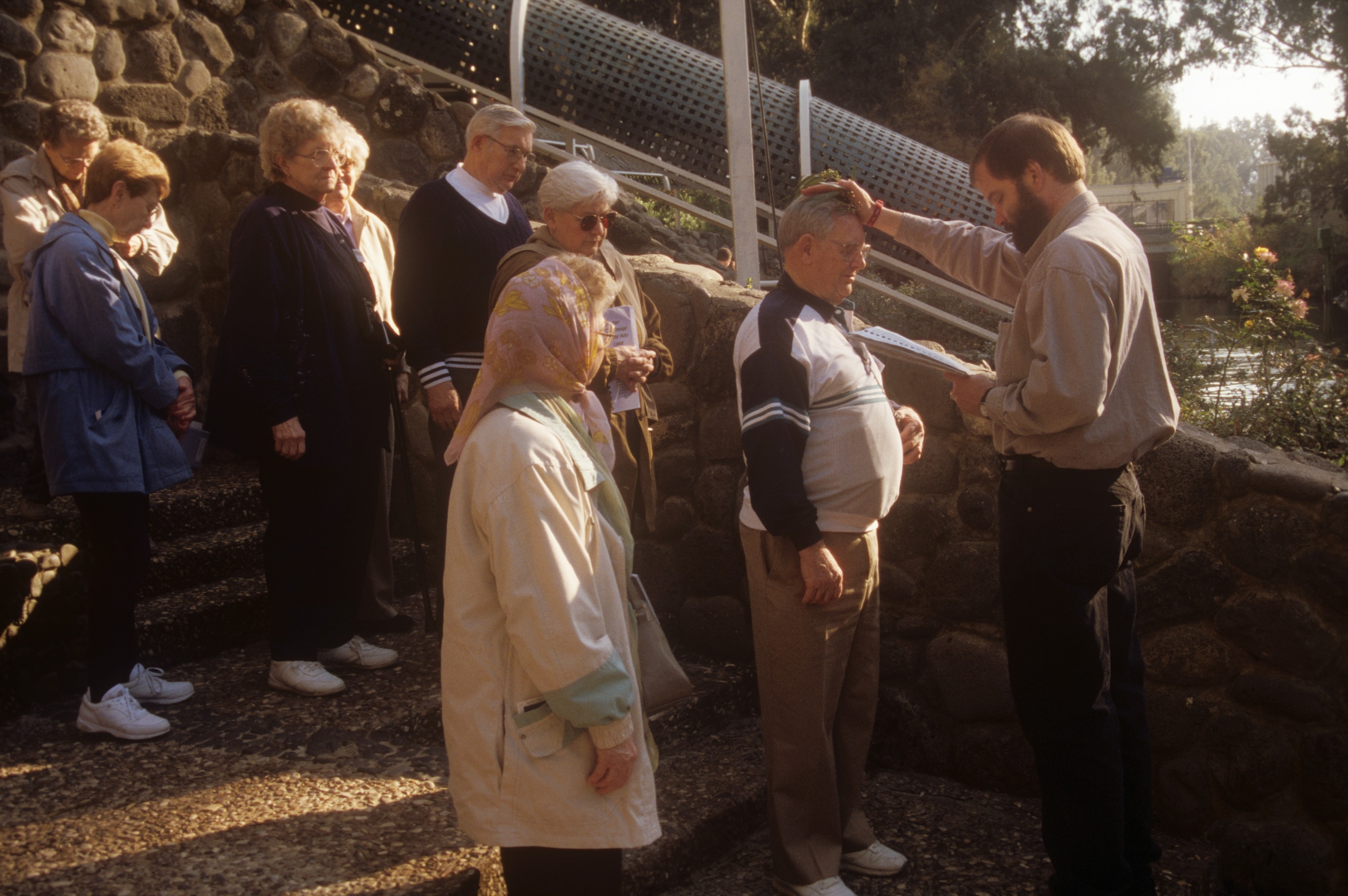 Pastor blessing a pilgrim during an outdoor ceremony at a sacred site in the Holy Land