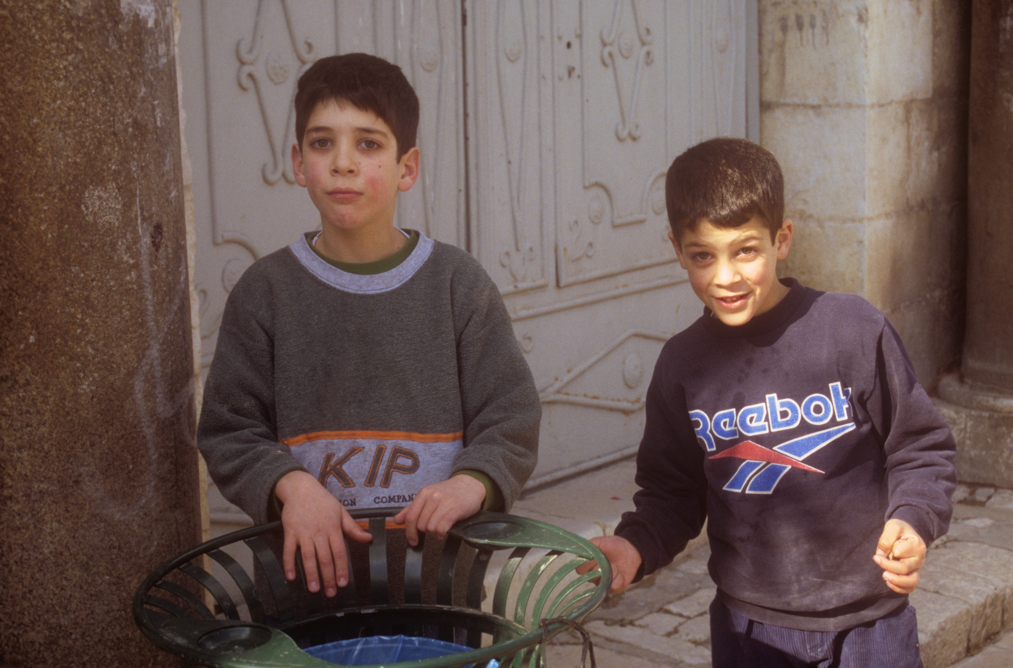 Two young boys standing together on a cobblestone street in the Holy Land