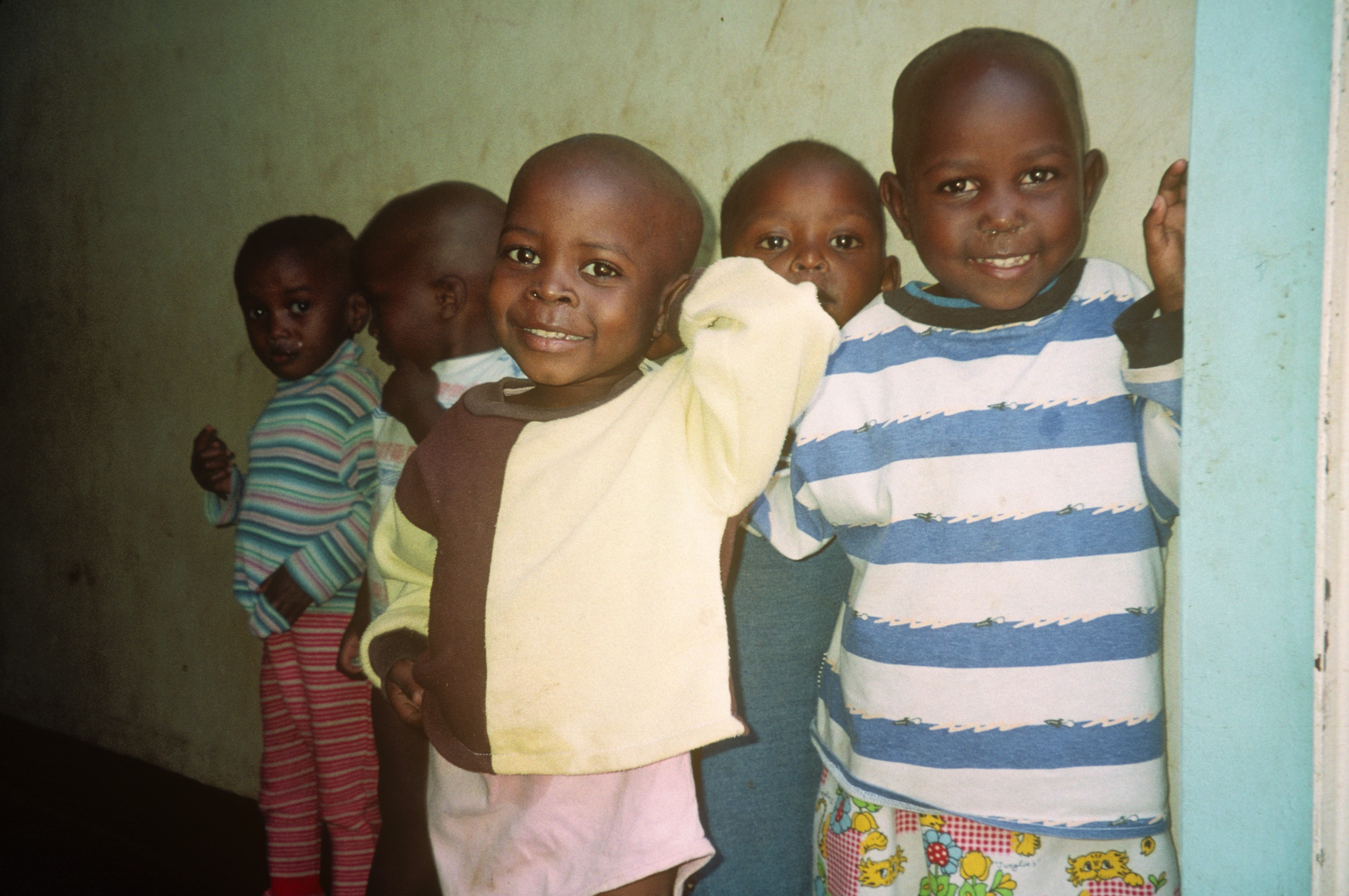 Group of young children smiling together in a doorway in Rwanda