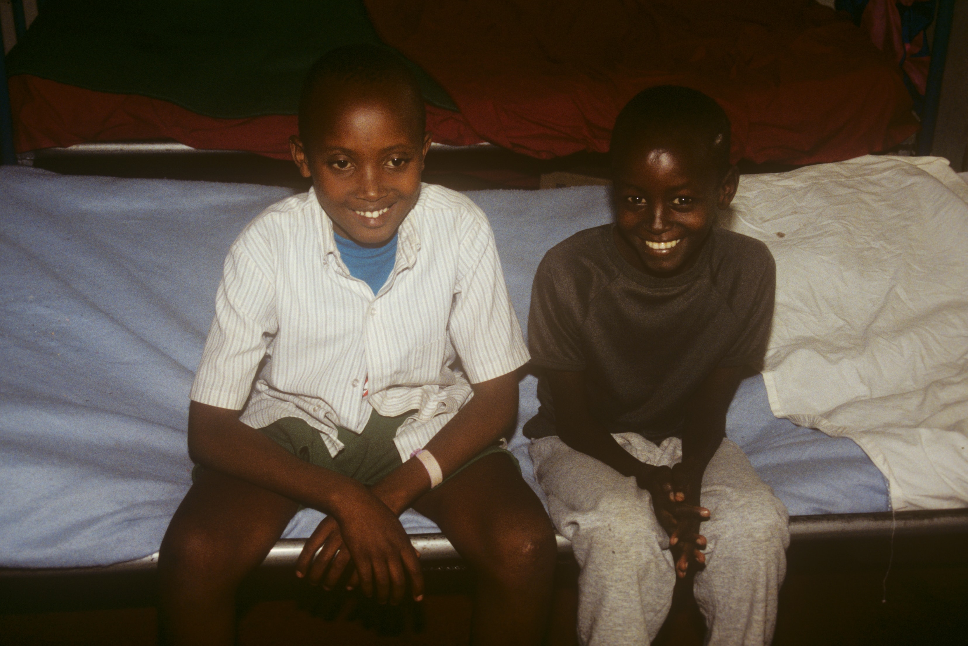 Two smiling boys sitting on a hospital bed in Rwanda
