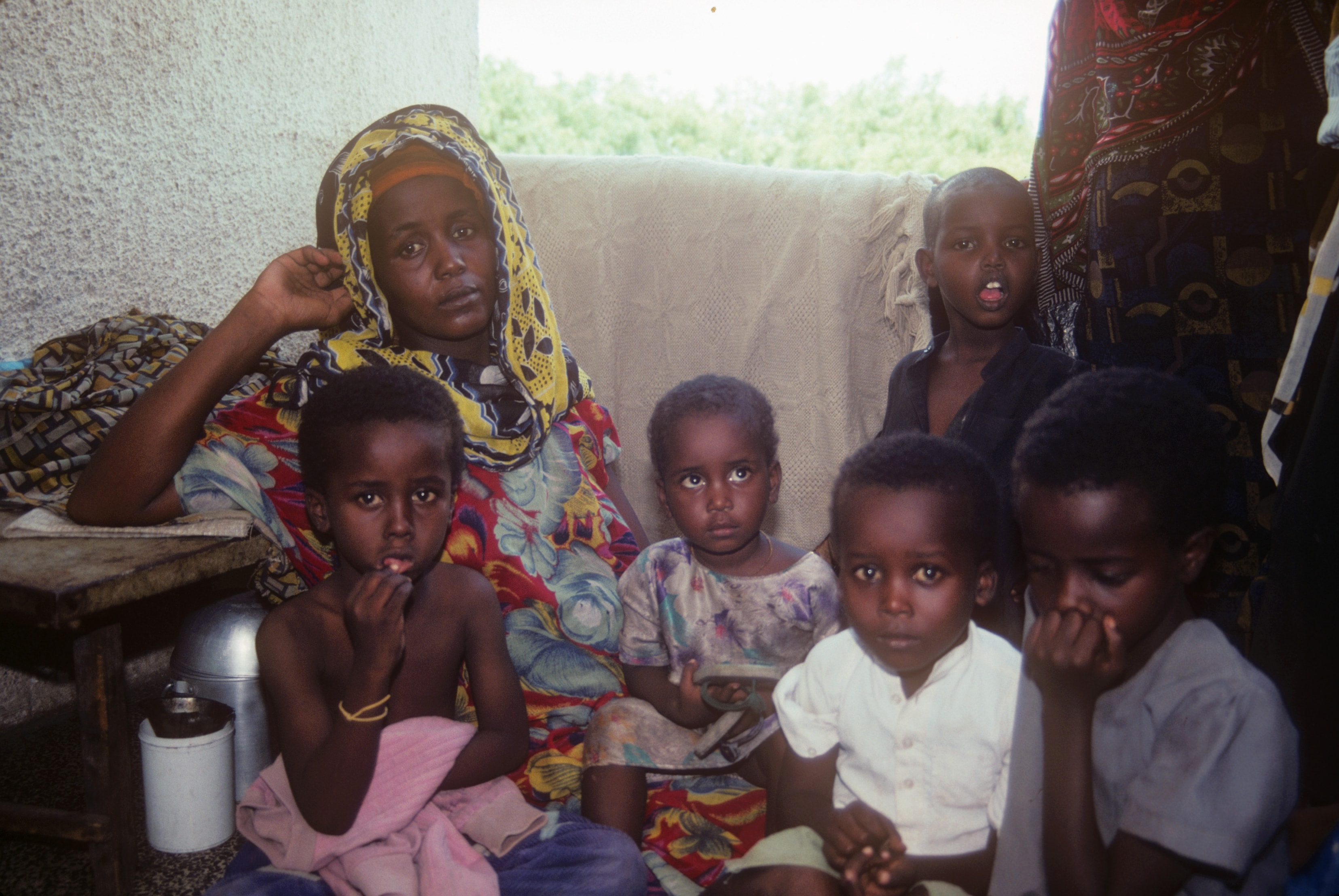 A mother in a colorful headscarf seated with four young children in Somalia