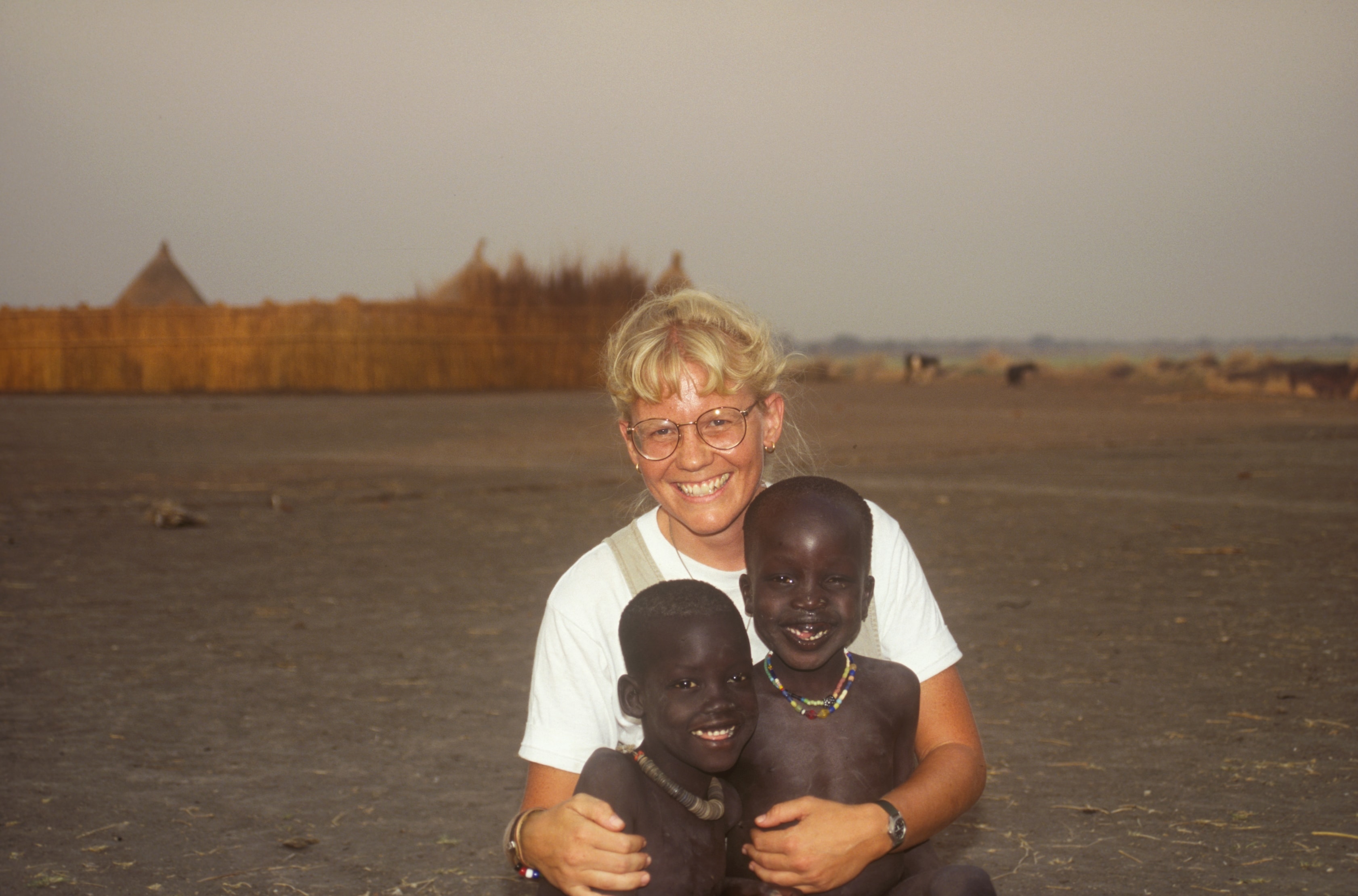 Dr. Susan Vitalis smiling and hugging two young children in Sudan