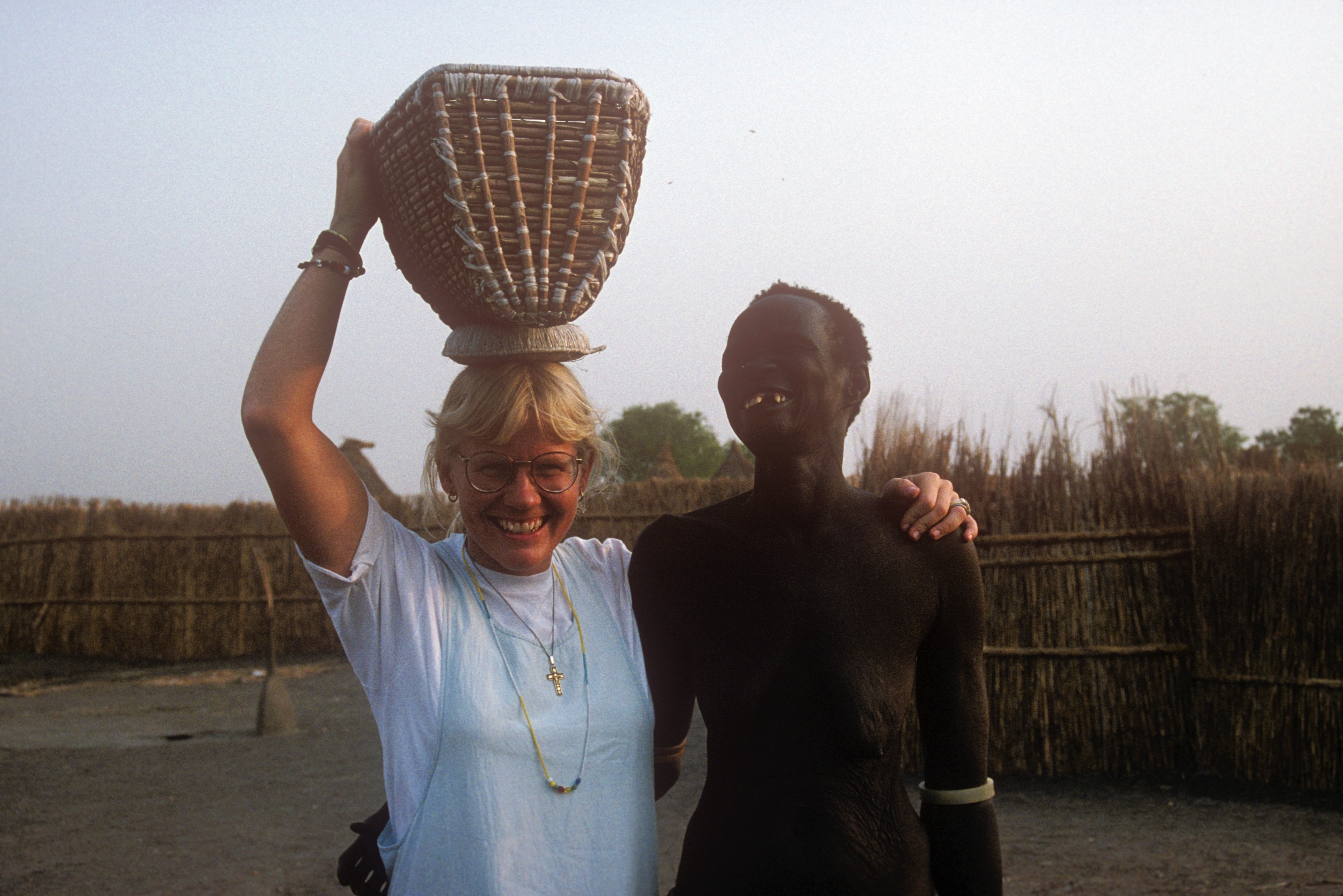 Dr. Susan Vitalis smiling beside a young child with a beaded necklace in Sudan